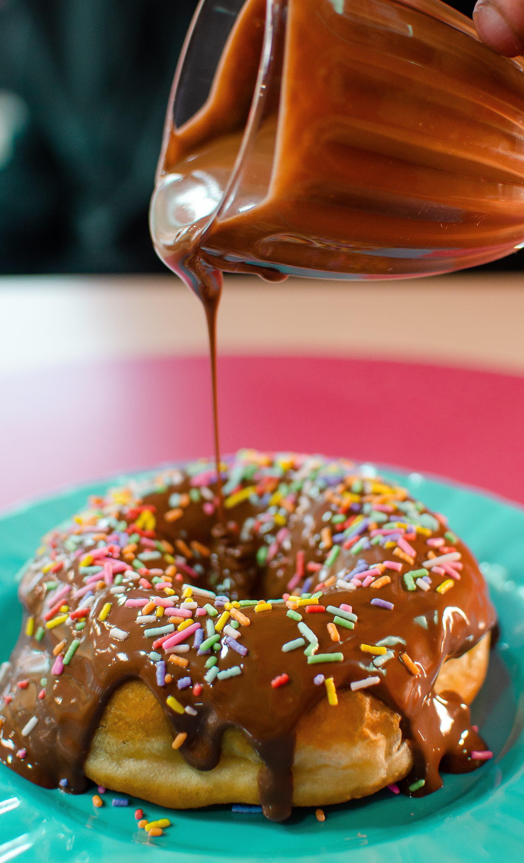 Calda sendo servida sobre donut O Tradicionalíssimo